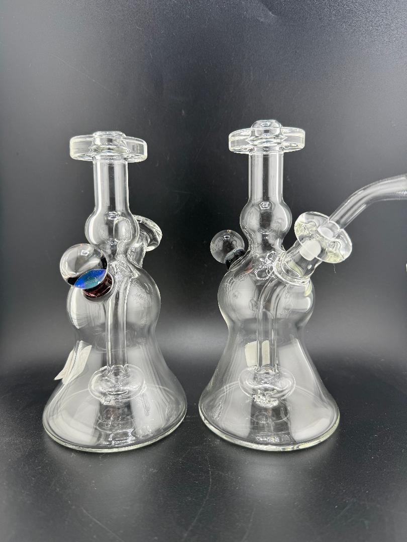Image of two handcrafted glass water pipes with unique designs showcased against a dark background.