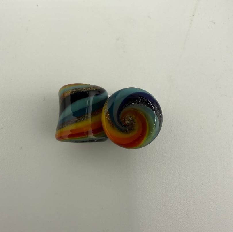 Colorful handcrafted borosilicate glass ear plugs showing swirled patterns, ideal for stretched ears.