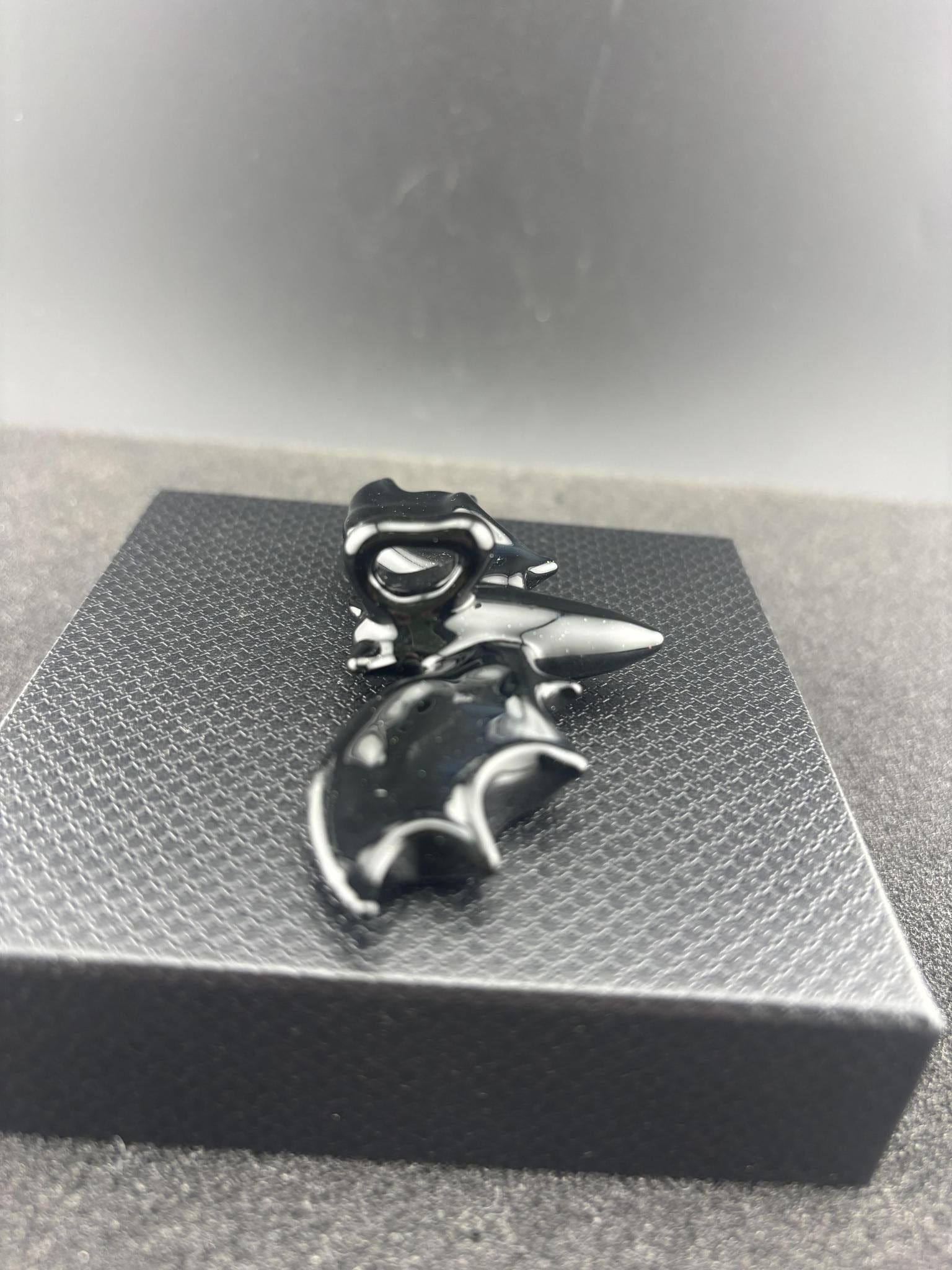 Filla John Bat Pendant displayed on a textured box, showcasing its unique black handcrafted design.