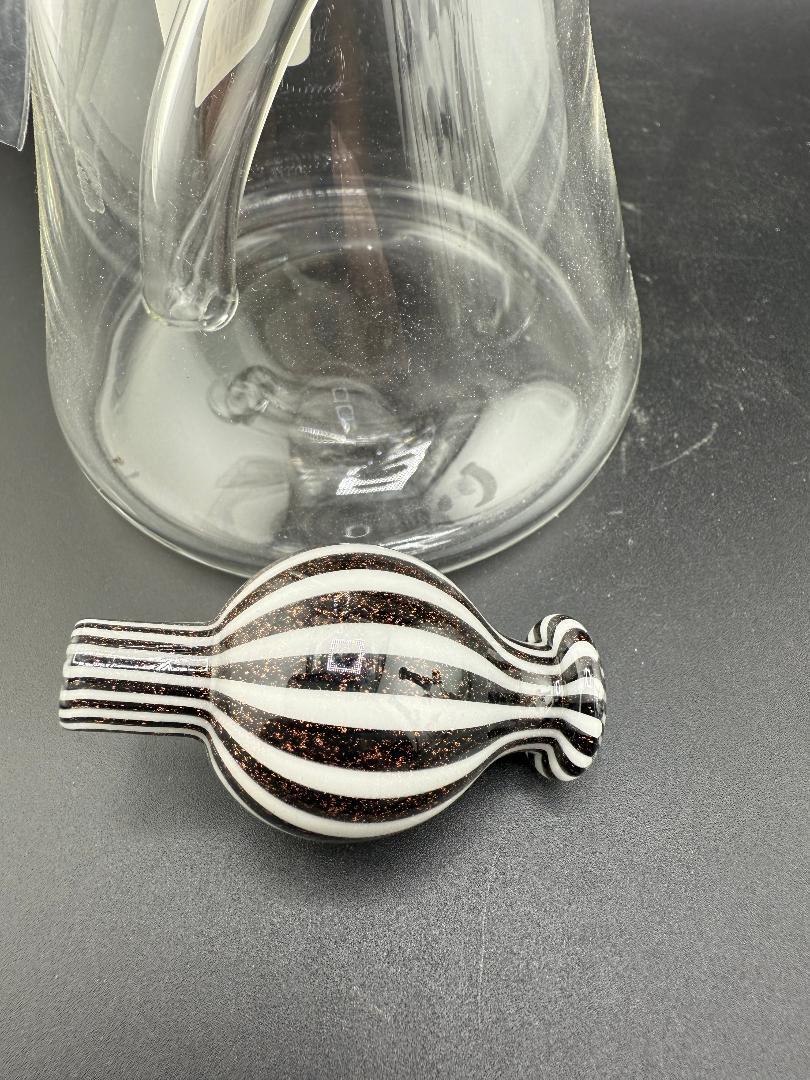 Filla John Glass Dichro Neck Beaker10mm 45° w/ Matching Cap and a clear glass container in background.