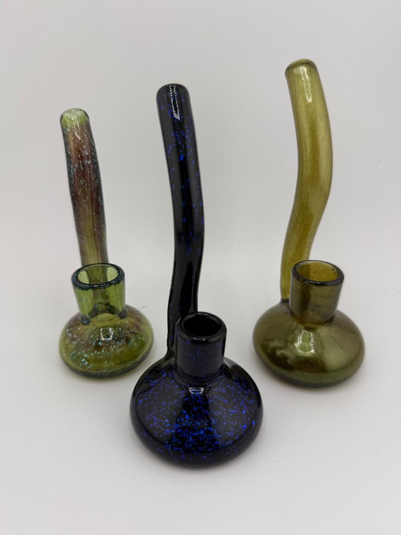 Three handcrafted glass dry rigs in varied colors and designs featuring dichroic accents and unique shapes.