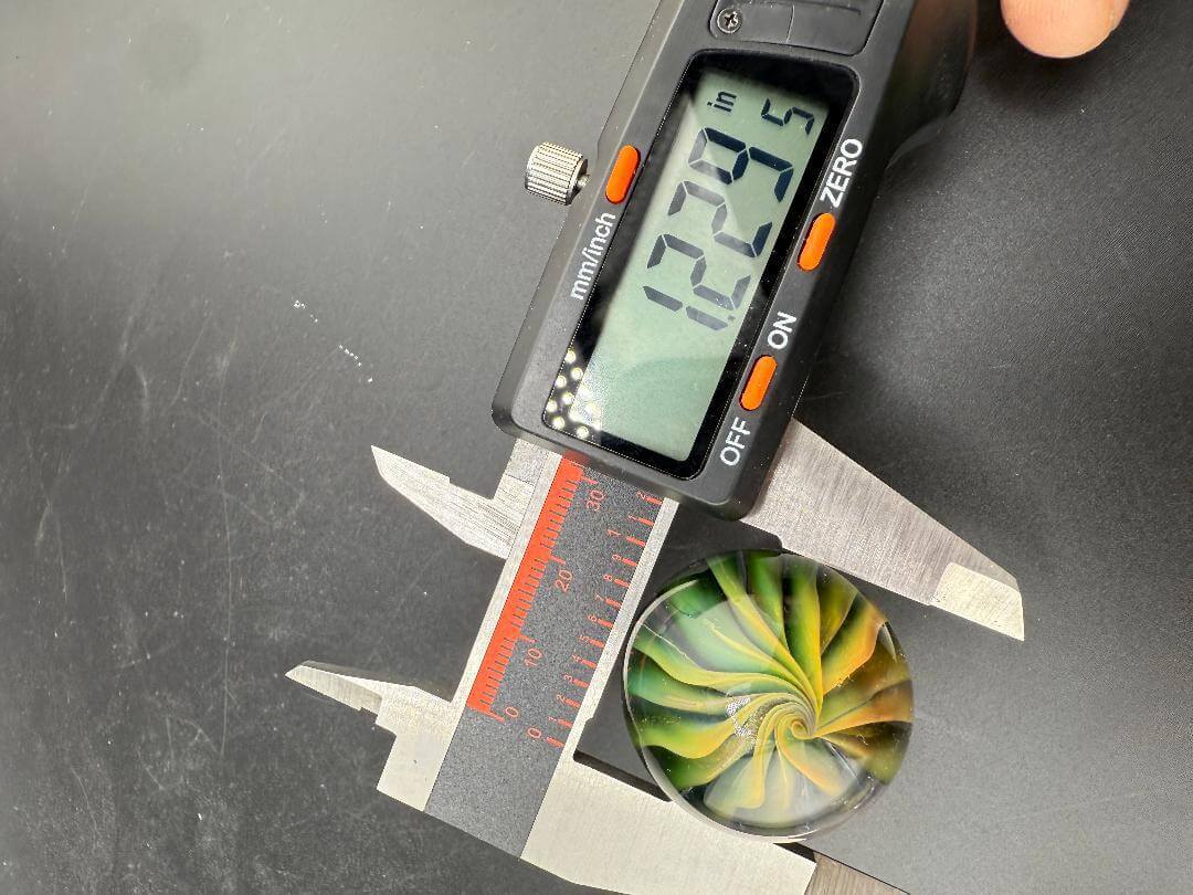 Filla John Glass Marble - Fumed Implosion Approx. 1.25" with measuring tool showing size.