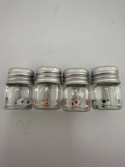 Set of four small glass jars with metal lids, each featuring a colorful dot design inside.