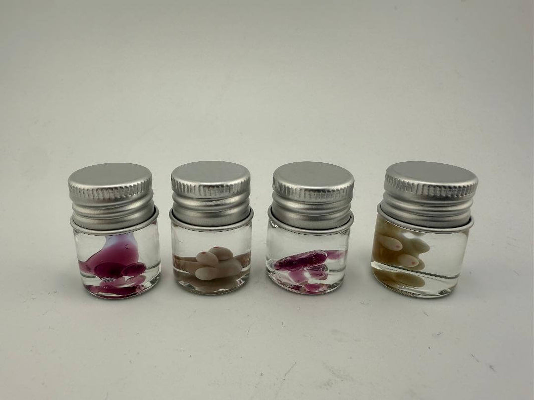 Four small jars with silver lids, each containing colorful glass terp pearls for dabbing and novelty art.