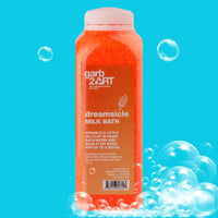 Garb2art Cosmetics Dreamsicle Milk Bath bottle with orange bath soak and bubbles on a blue background.