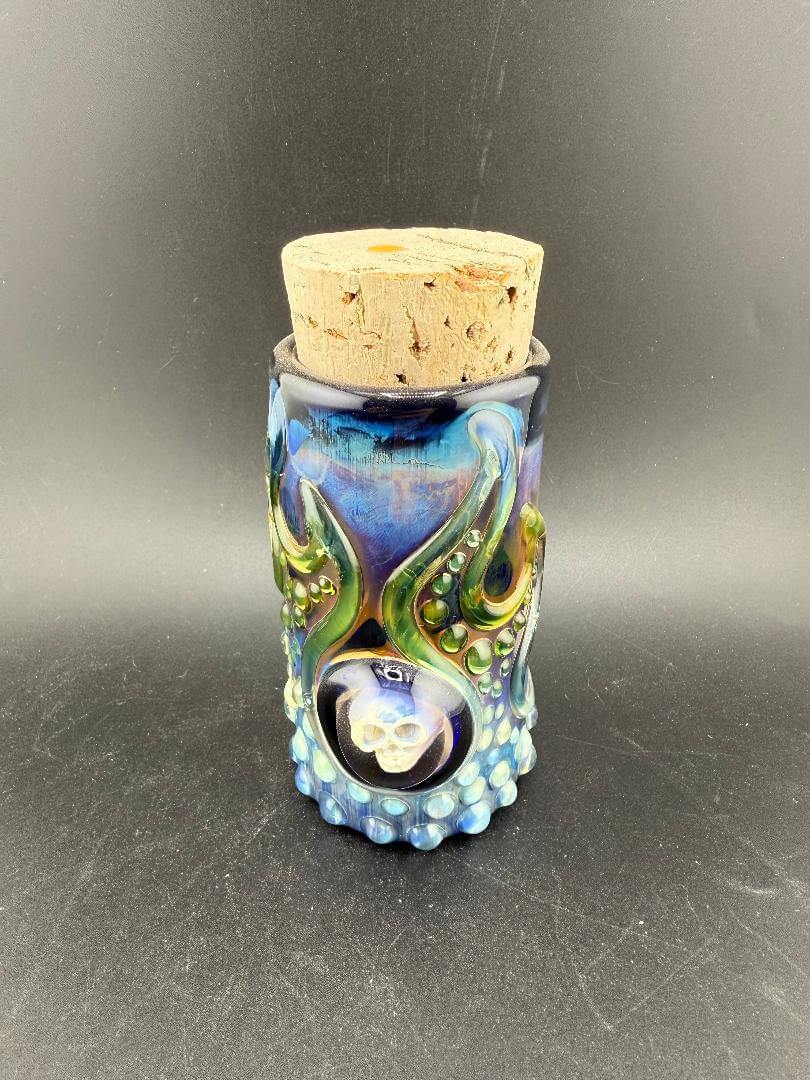 Glass Distractions Fumed Skull Cork Jar with intricate blue design and cork lid, showcasing artistry and unique color transitions.