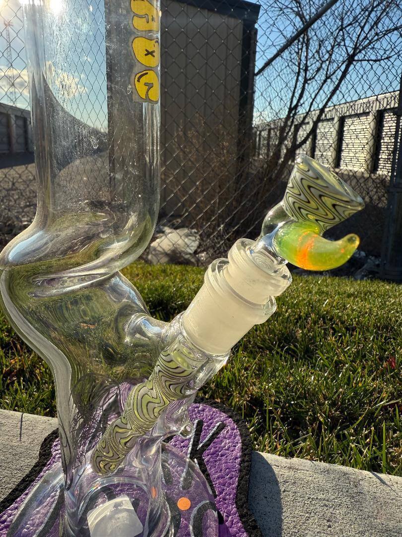 Highgrade Glass Flower Straight Tube – Green & White Wig Wag Color Accent Pistol Loop 14mm 45° displayed outdoors.