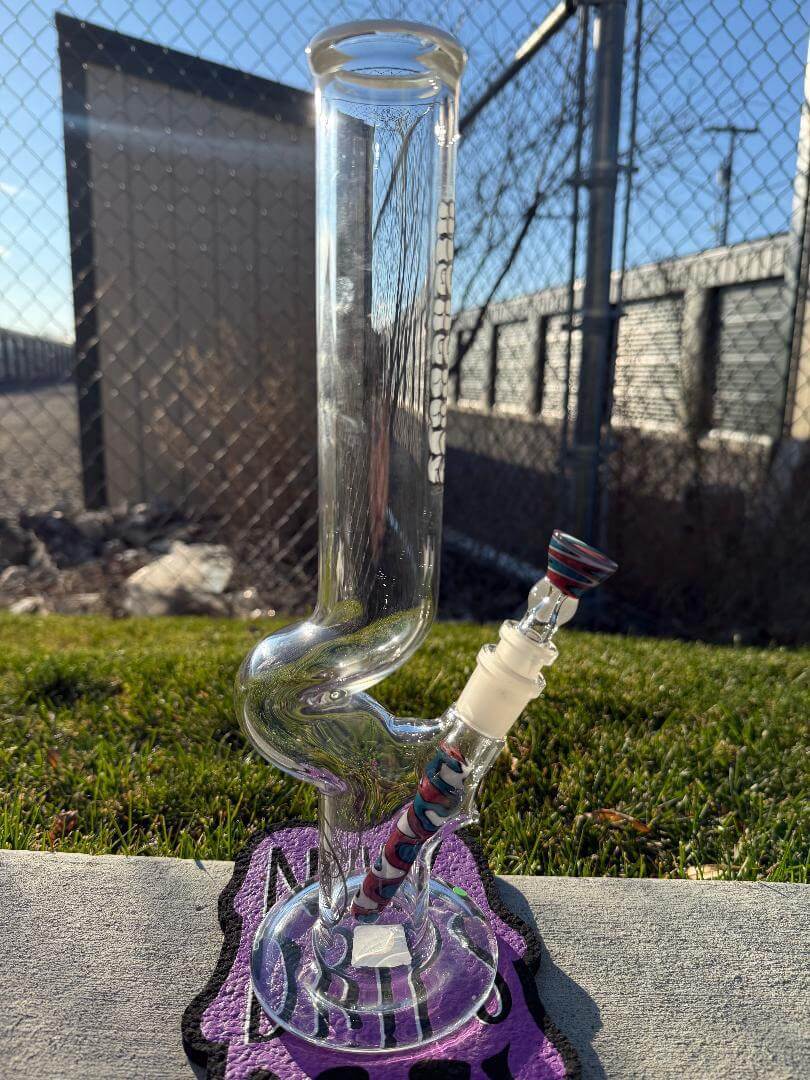 Highgrade Glass Flower Straight Tube – Red, White & Blue Wig Wag Color Accent Pistol Loop 14mm 45° on display outdoors.