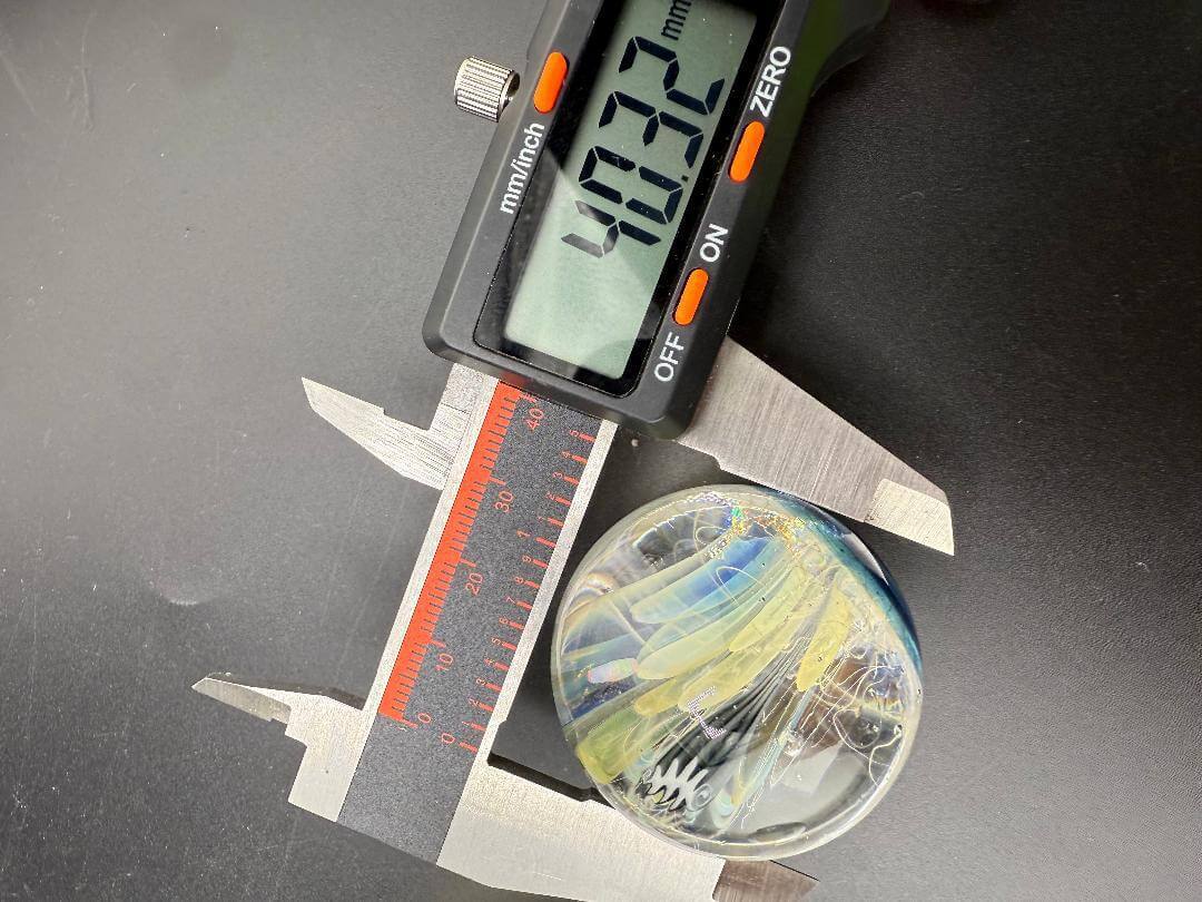 Highgrade Glass Marble - 40mm Millie Implosion w/ Opal Encasment with caliper measuring diameter.