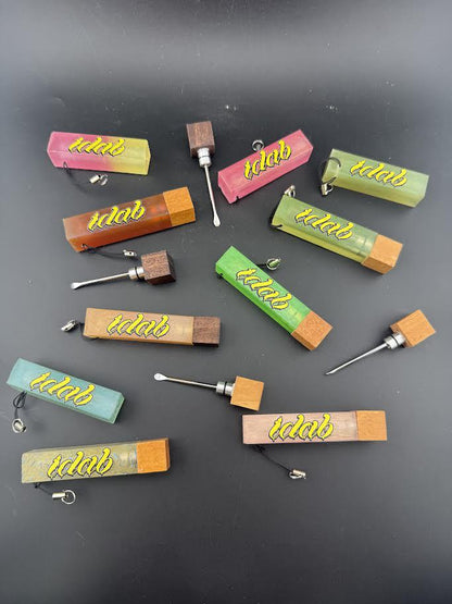 Collection of colorful Idab Dabber Guard tools for concentrate sessions laid out on a black background.