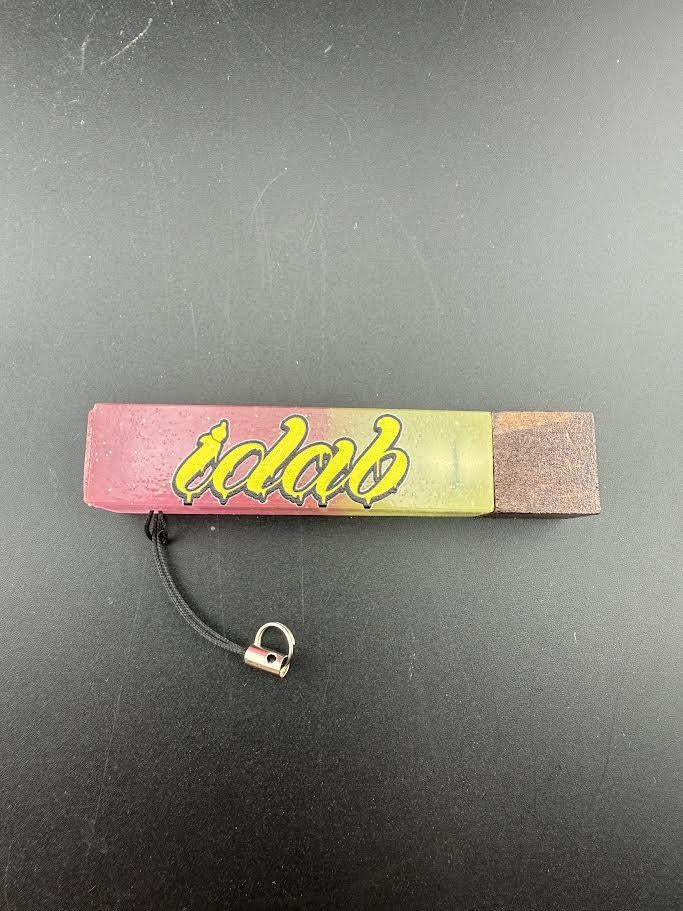 iDab Dabber Guard on a black surface, featuring a colorful design and built-in stand for concentrates.