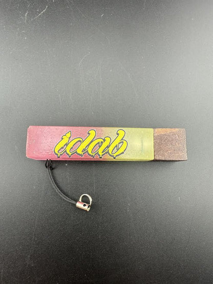 iDab Dabber Guard on a black surface, featuring a colorful design and built-in stand for concentrates.