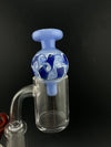 Import Bubble Cap 25mm - Dot Stack on a flat-top quartz banger, featuring intricate blue and white swirl design.