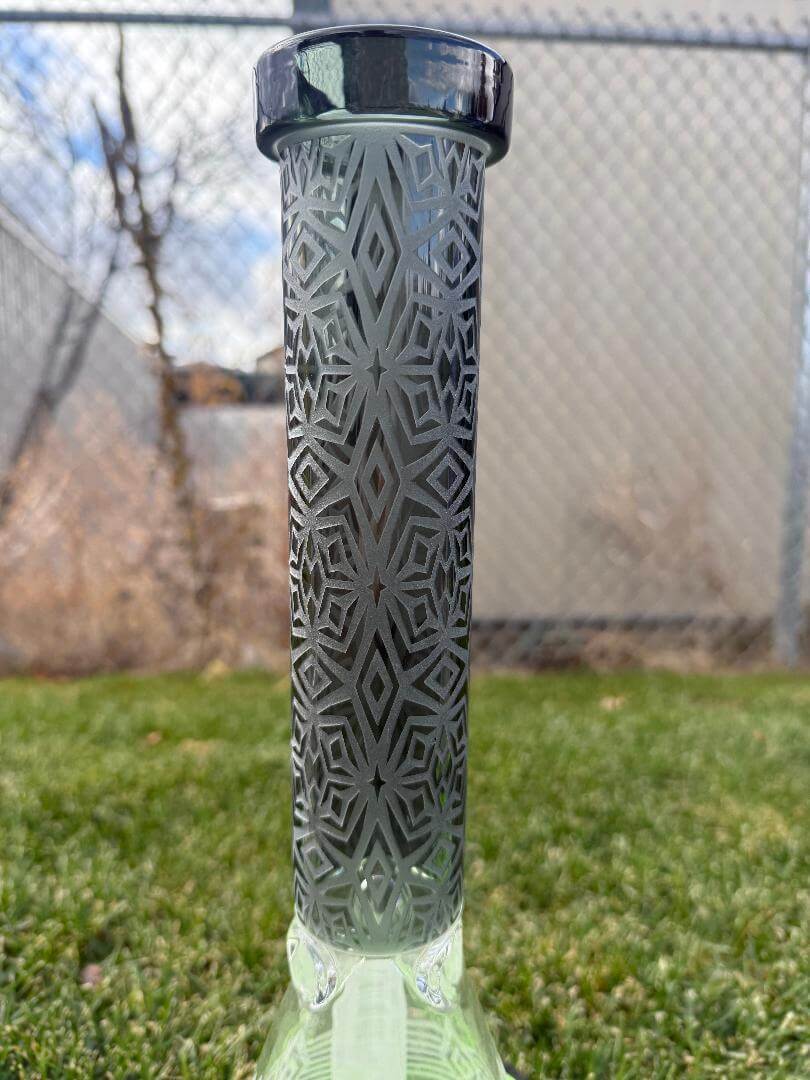 Import Frosted Stars Beaker 14mm 45° showcasing intricate etched pattern and sleek design on a grassy background.