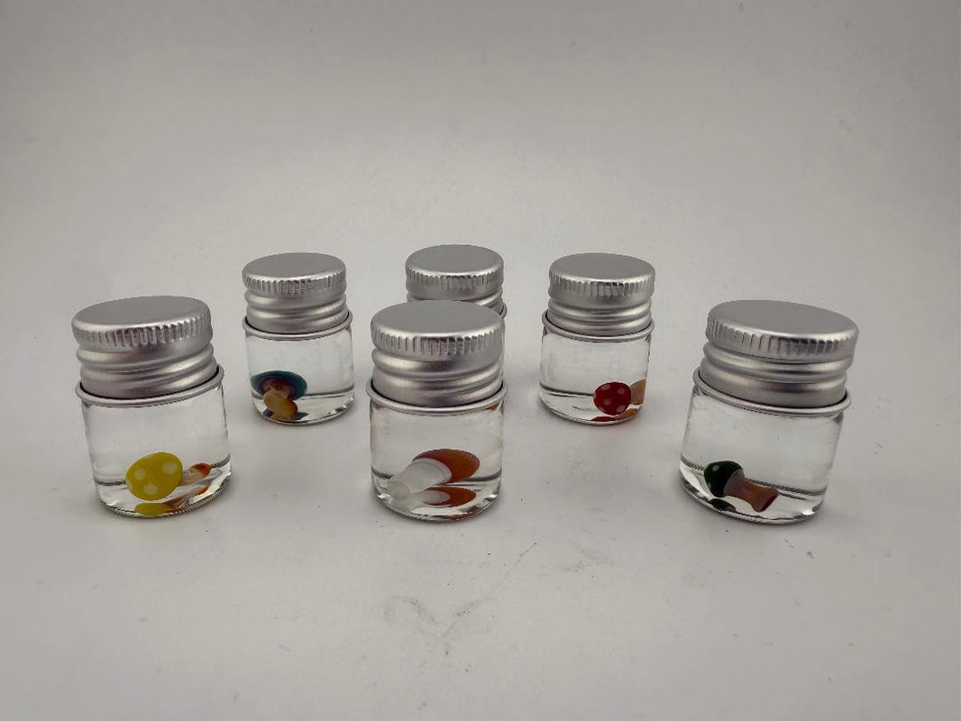 Six glass jars filled with colorful terp pearls in various shades, each with a metal screw cap, arranged on a white background.