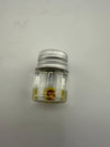 Small glass jar with a silver lid containing a yellow and red substance.