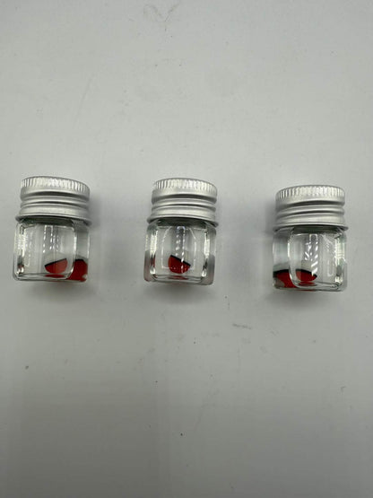Three small jars containing red glass pieces, ideal for crafting or storage, on a white background.