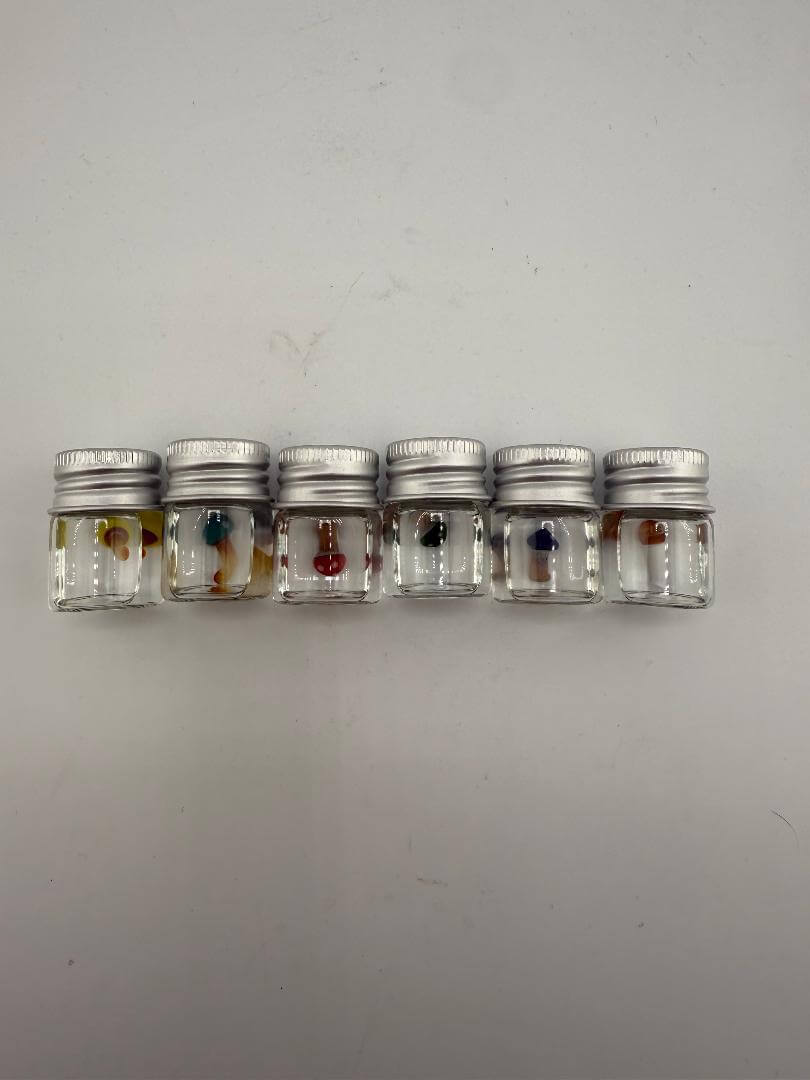 Colorful Lucky Gnome Glass Terp Pearls in clear jars, showcasing unique mushroom designs for an enhanced dab experience.