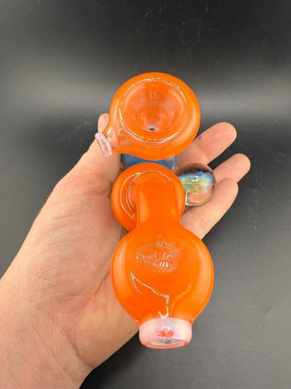 Mank Glass Sherlock Pipe - Orange And Blue Swiss Hole w/ Implosion Marble held in hand with vibrant colors and design.