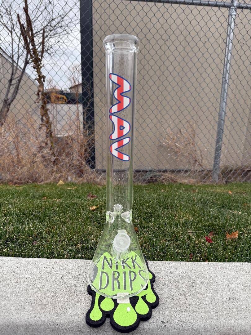 MAV Glass "18 Beaker 14mm 45° - American Flag" showcased on a green grass background with a unique base design.