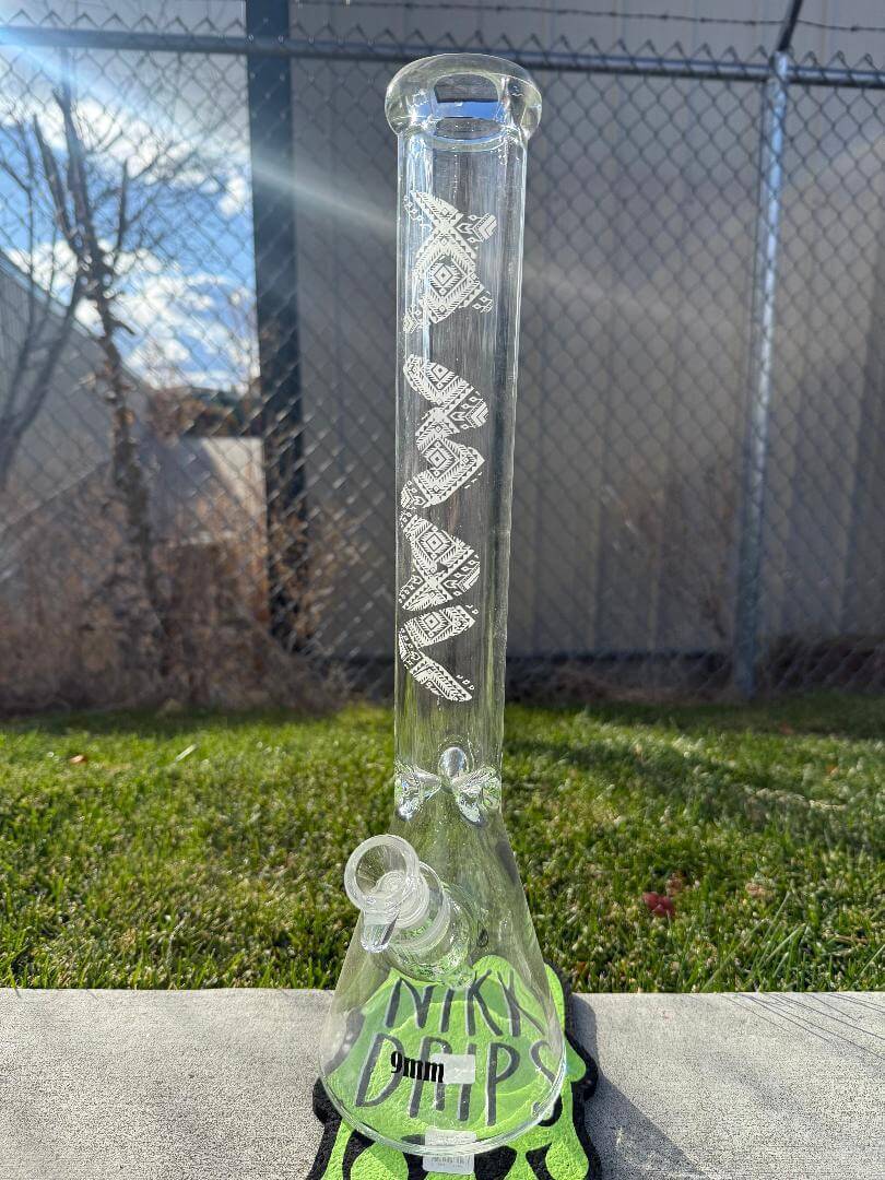 MAV Glass 18' Beaker 14mm 45° - Glow In The Dark Tribal displayed outdoors on green grass.