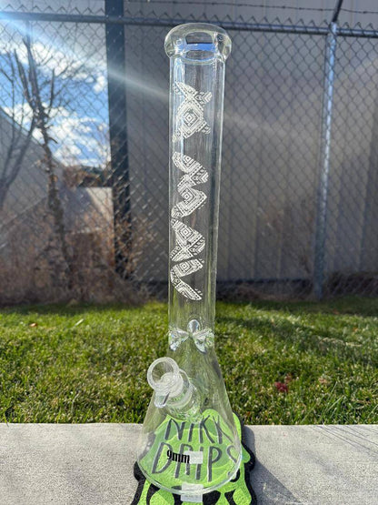 MAV Glass 18' Beaker 14mm 45° - Glow In The Dark Tribal displayed outdoors on green grass.