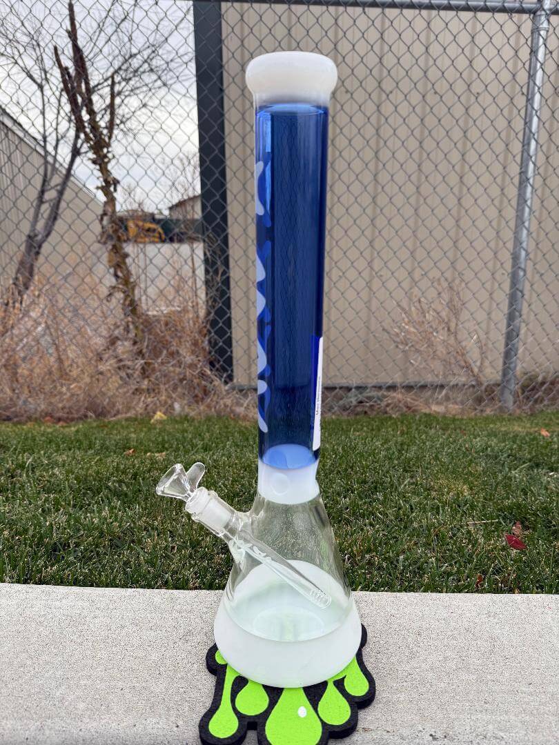MAV Glass18" Beaker 14mm 45°- Hermosa Blue & White displayed outdoors on a green and black mat.