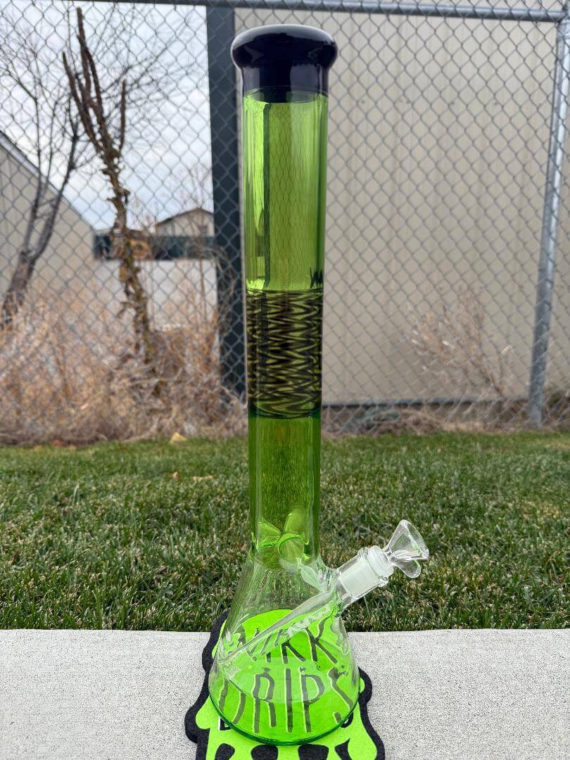 MAV Glass 18" Reversal Beaker 14mm 45° featuring a green body and clear bowl, placed on a grass surface.