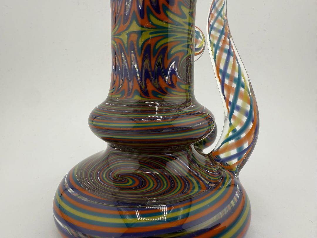 Close-up of Mcdoogle Glass Wig Wag Rig in vibrant teal, yellow, and orange swirl patterns, 10mm 90°