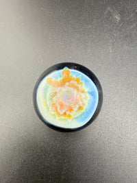 Mcdoogle Glass Marble - 22mm No Fume Fume Tech w/ Purple Flower Dot Stack Backer on a dark surface.