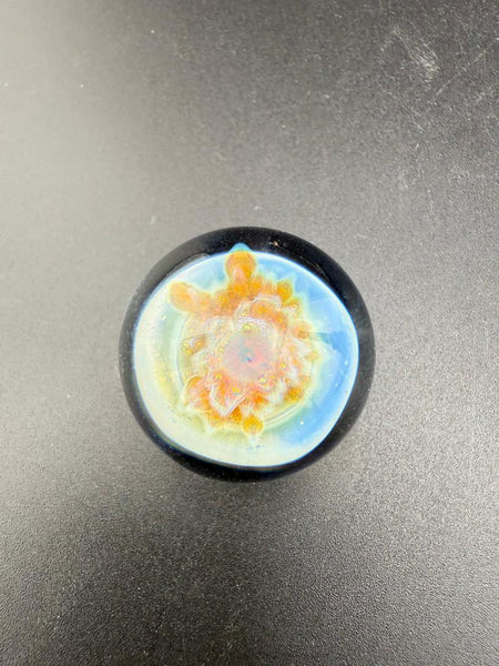 Mcdoogle Glass Marble - 22mm No Fume Fume Tech w/ Purple Flower Dot Stack Backer on a dark surface.