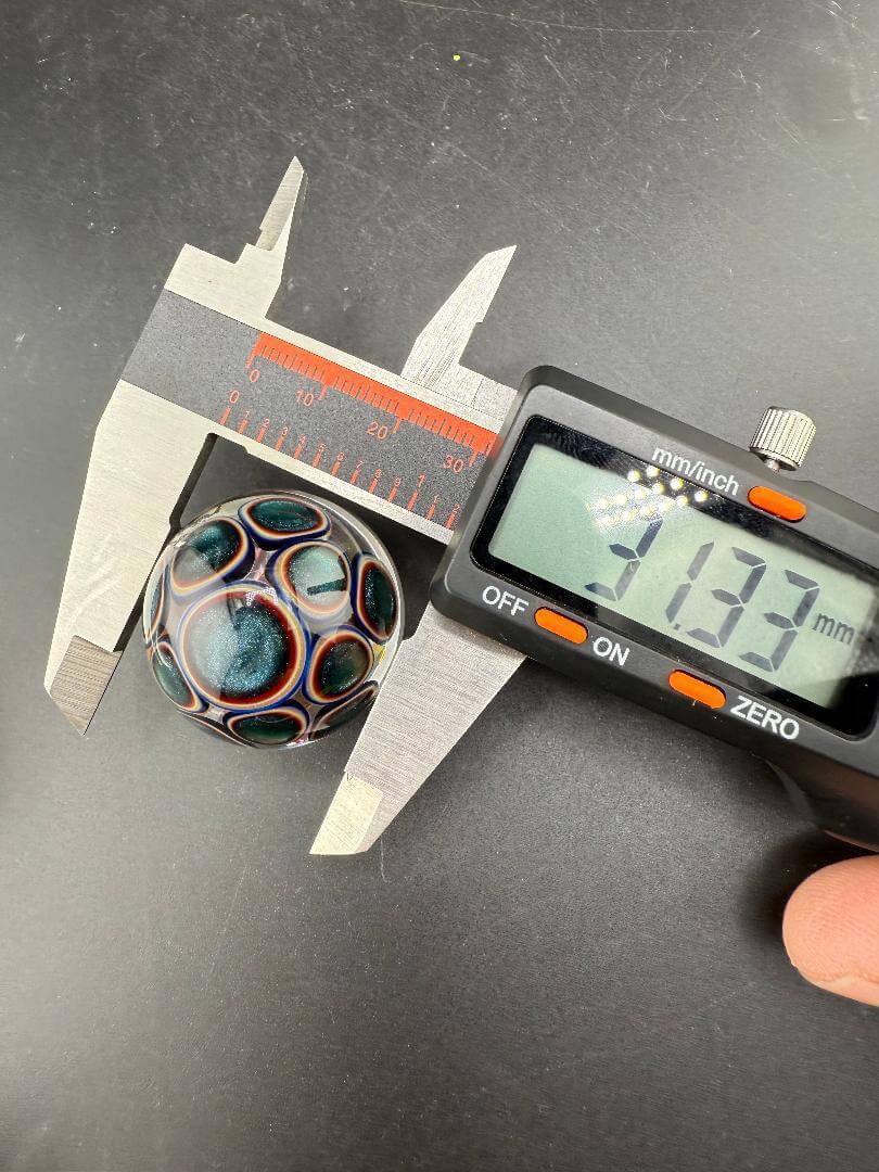Mcdoogle Glass Marble - 31mm Fume Implosion being measured with calipers for precise diameter.