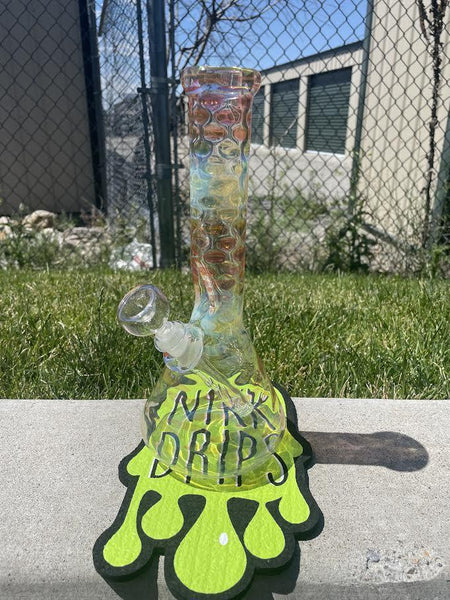 gold fumed flower beaker with vibrant colors displayed on grassy surface.