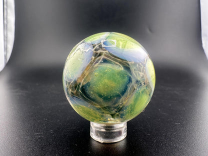Mop Head Glass Marble - Fumed Implosion Swirl showcased on a stand, featuring vibrant colors and swirling designs.