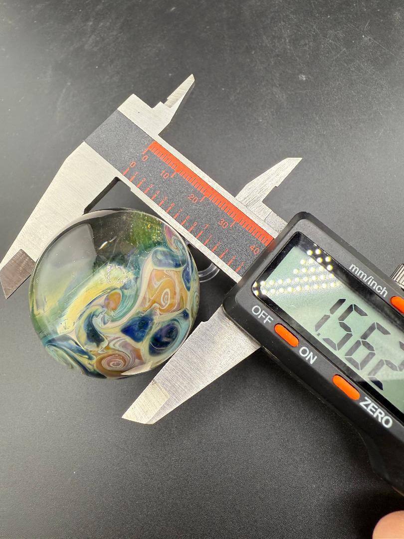 Mop Head Glass Marble - Space Vortex 1.2" - 1.5" being measured with calipers for size and detail.