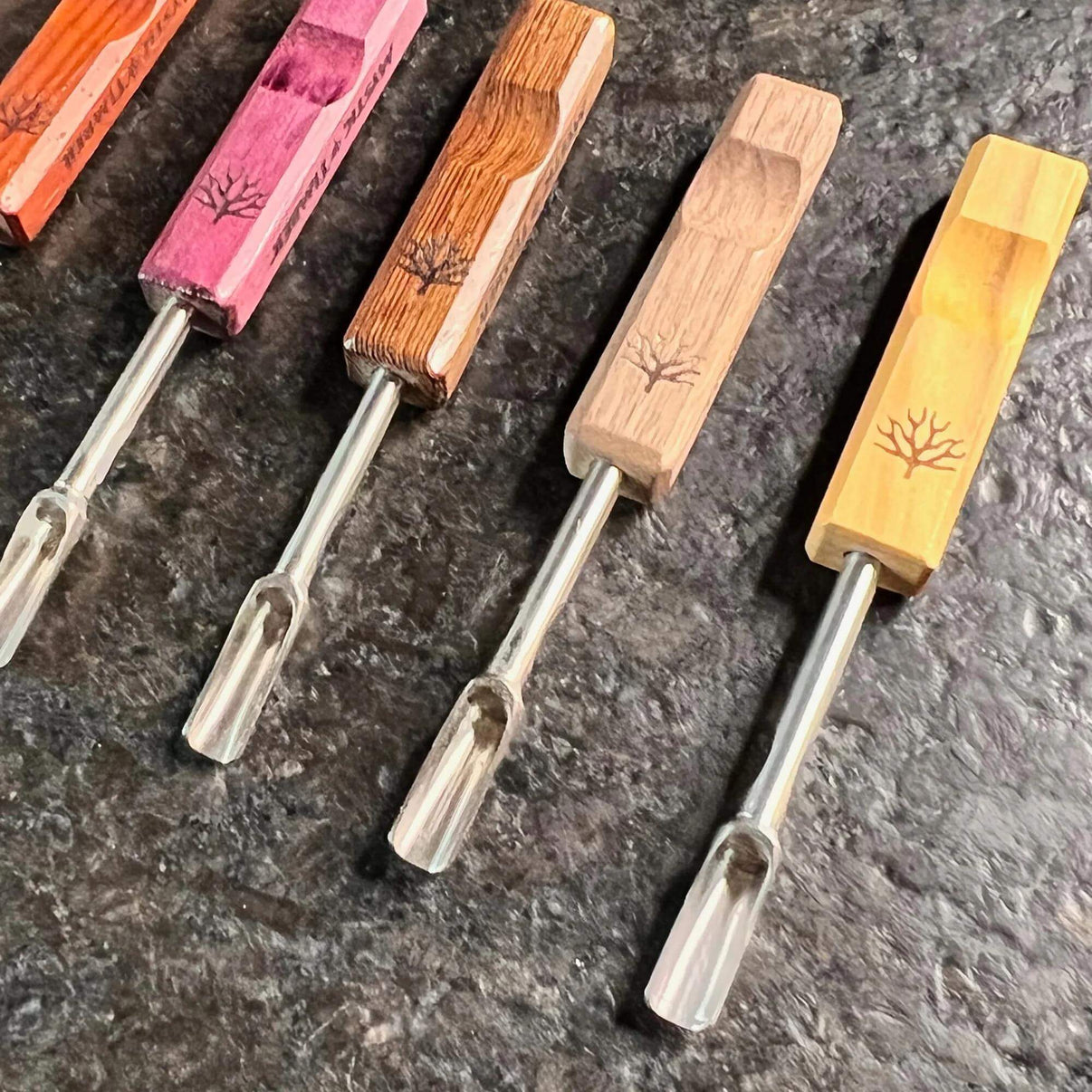 Mystic Timber Dab Tool - Pocket Scoop collection of handcrafted dabbers in various wood finishes on a dark surface.