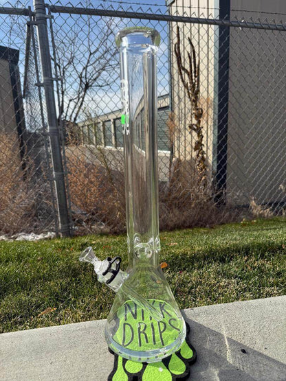 Thick Ass Glass (TAG) Beaker Sandblasted 18" 14mm 45° standing outdoors with a unique design and green accents.