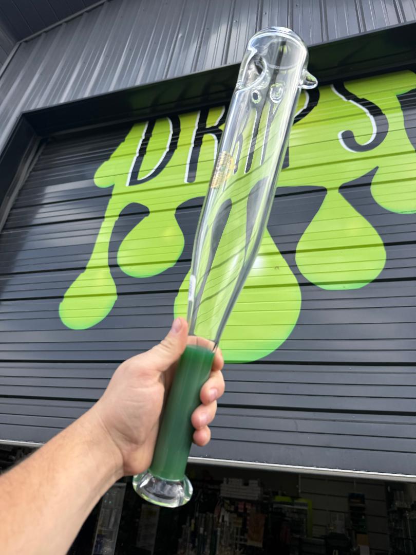 On Point Glass Baseball Bat  - Green held up in front of a colorful shop backdrop.