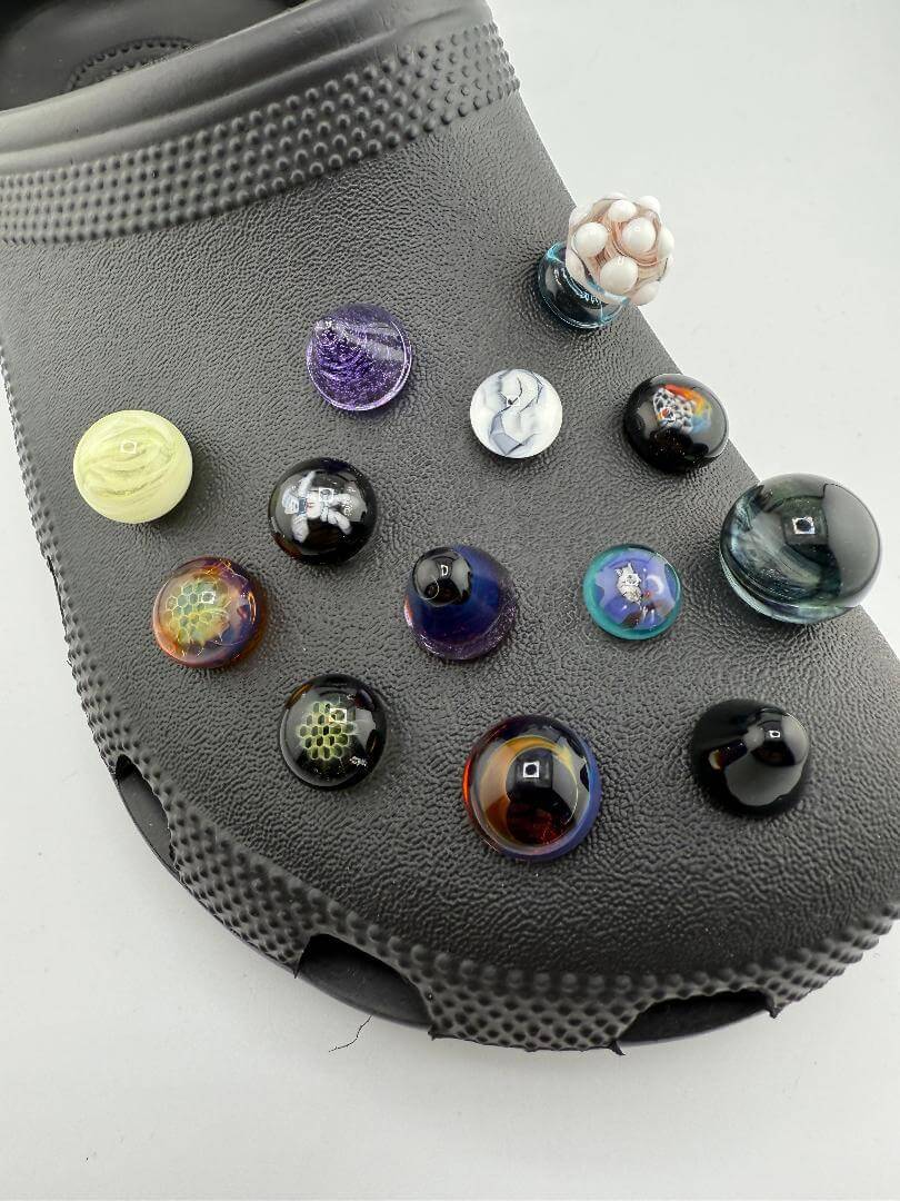 Colorful glass giblets on a textured black Croc shoe, showcasing unique pop culture designs and vibrant colors.