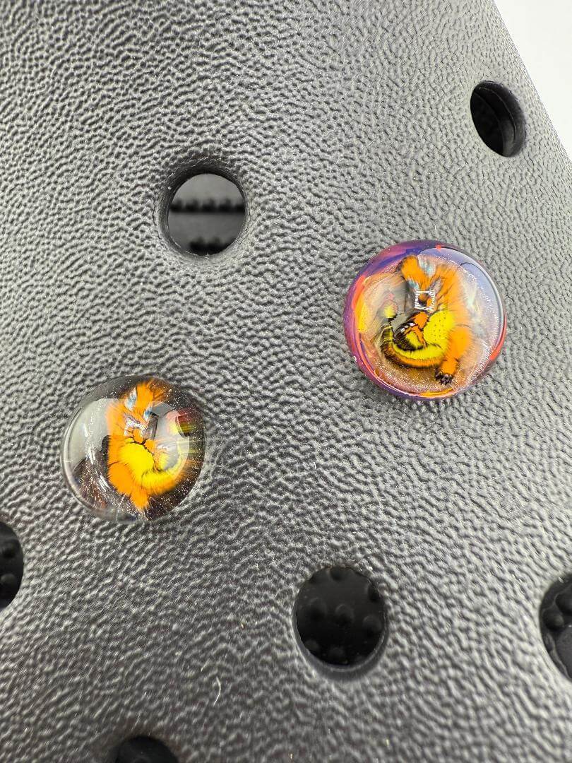 Close-up of Paulson Pieces glass Kroc giblets featuring pop culture designs on a textured black surface.