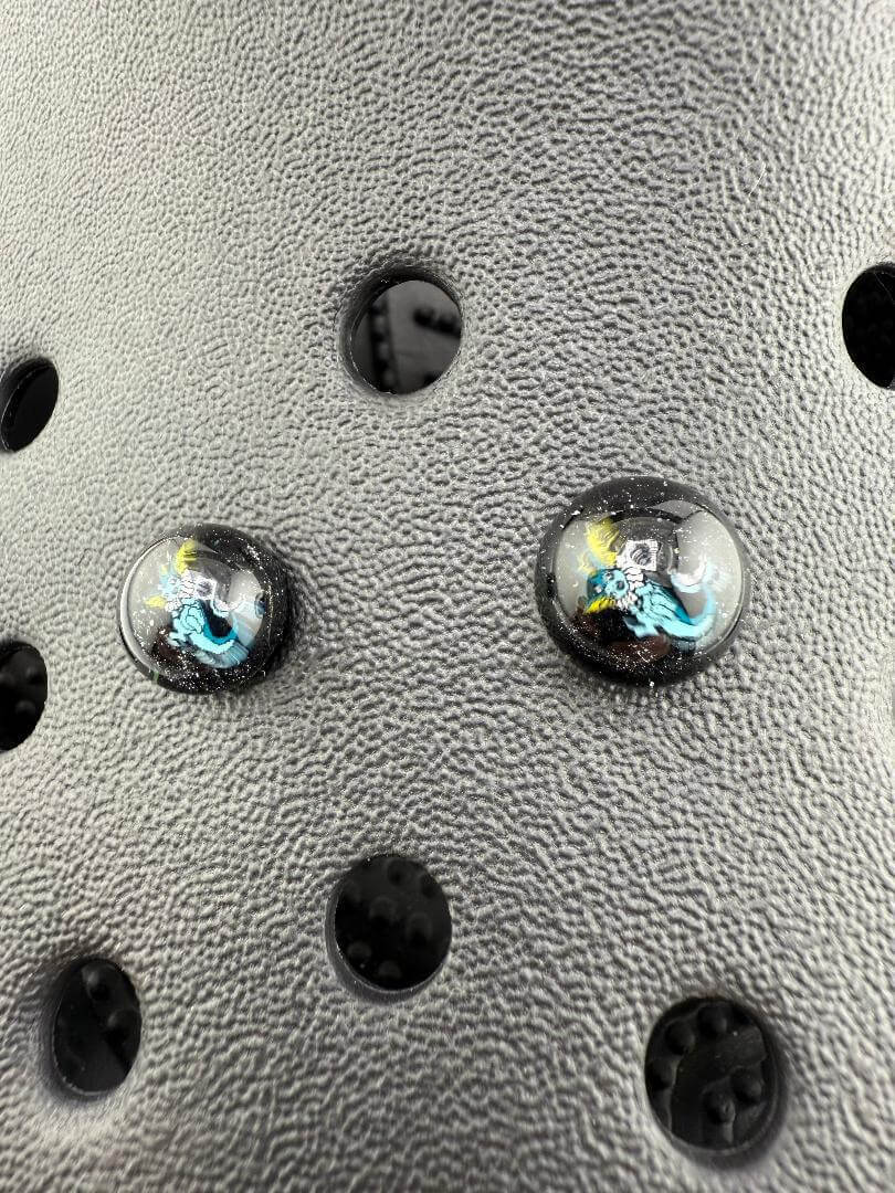Close-up of Paulson Pieces glass Millie Kroc giblets showcasing intricate pop culture designs on a textured background.