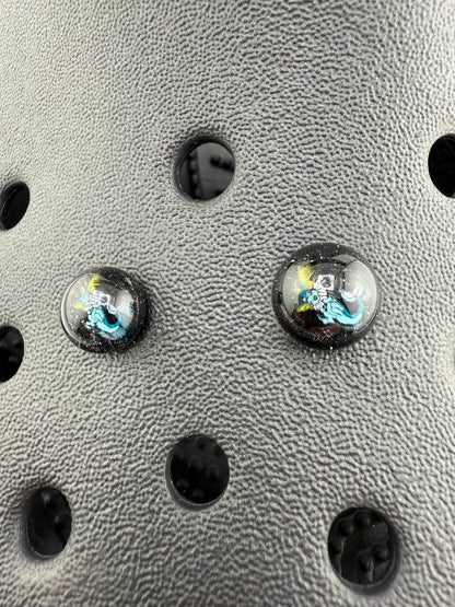 Close-up of Paulson Pieces glass Millie Kroc giblets showcasing intricate pop culture designs on a textured background.