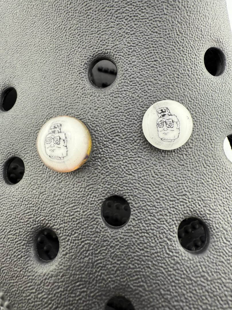 Close-up of Paulson Pieces glass Kroc Giblets featuring detailed pop culture designs on a textured black surface.