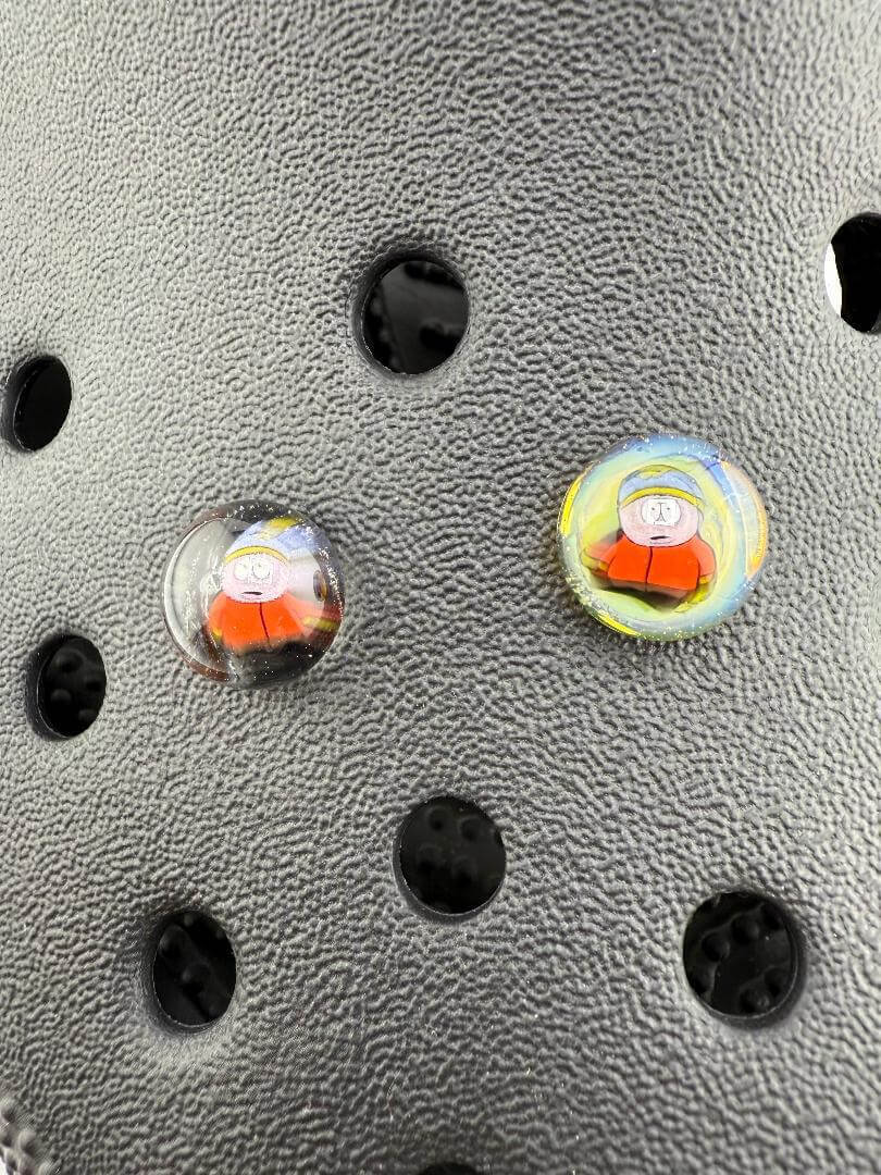 Close-up of Paulson Pieces Glass Millie Kroc Giblets featuring pop culture icons on textured background.