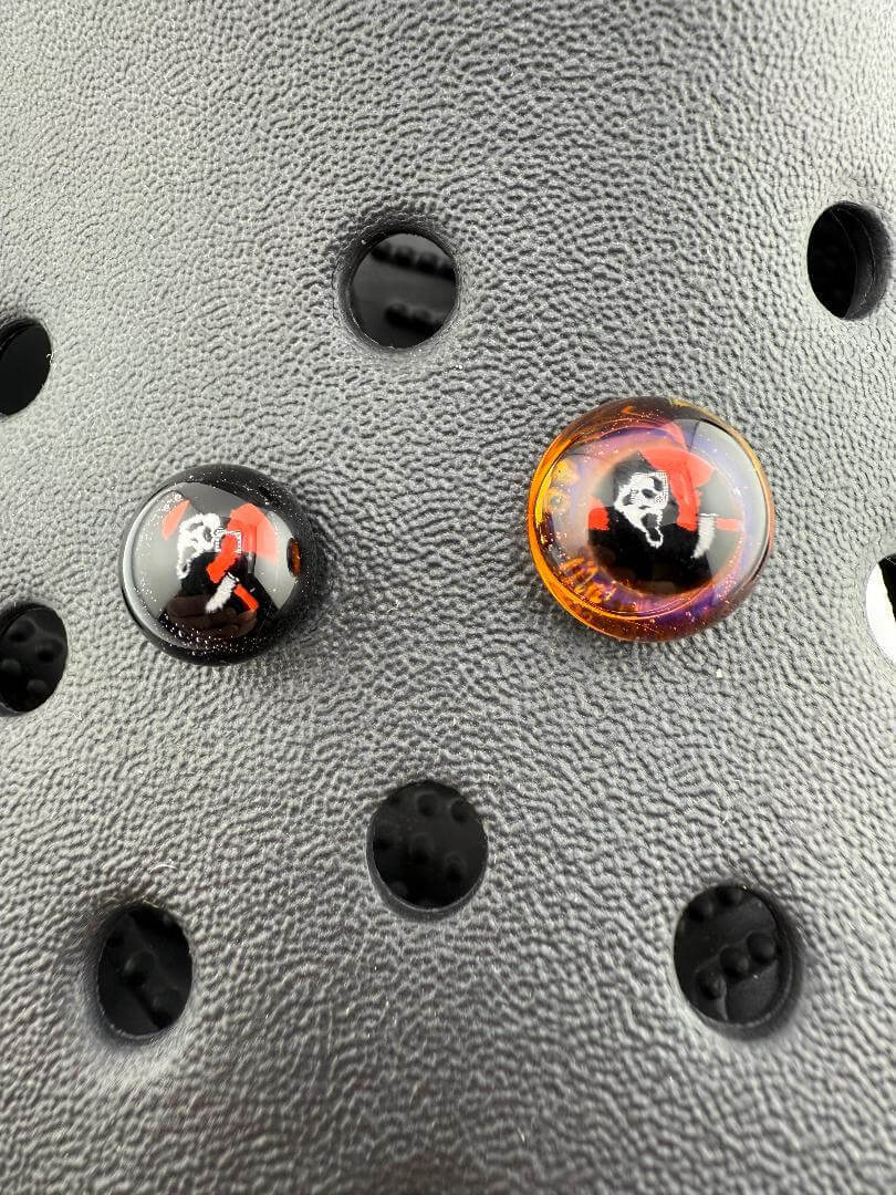 Close-up of Paulson Pieces Glass Kroc Giblets showcasing two handcrafted glass accessories with pop culture designs.