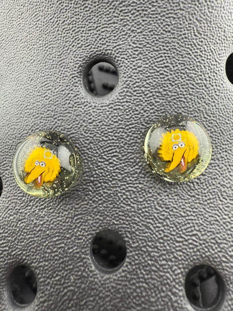 Two handcrafted glass Kroc giblet pieces featuring a yellow pop culture character on a textured background.