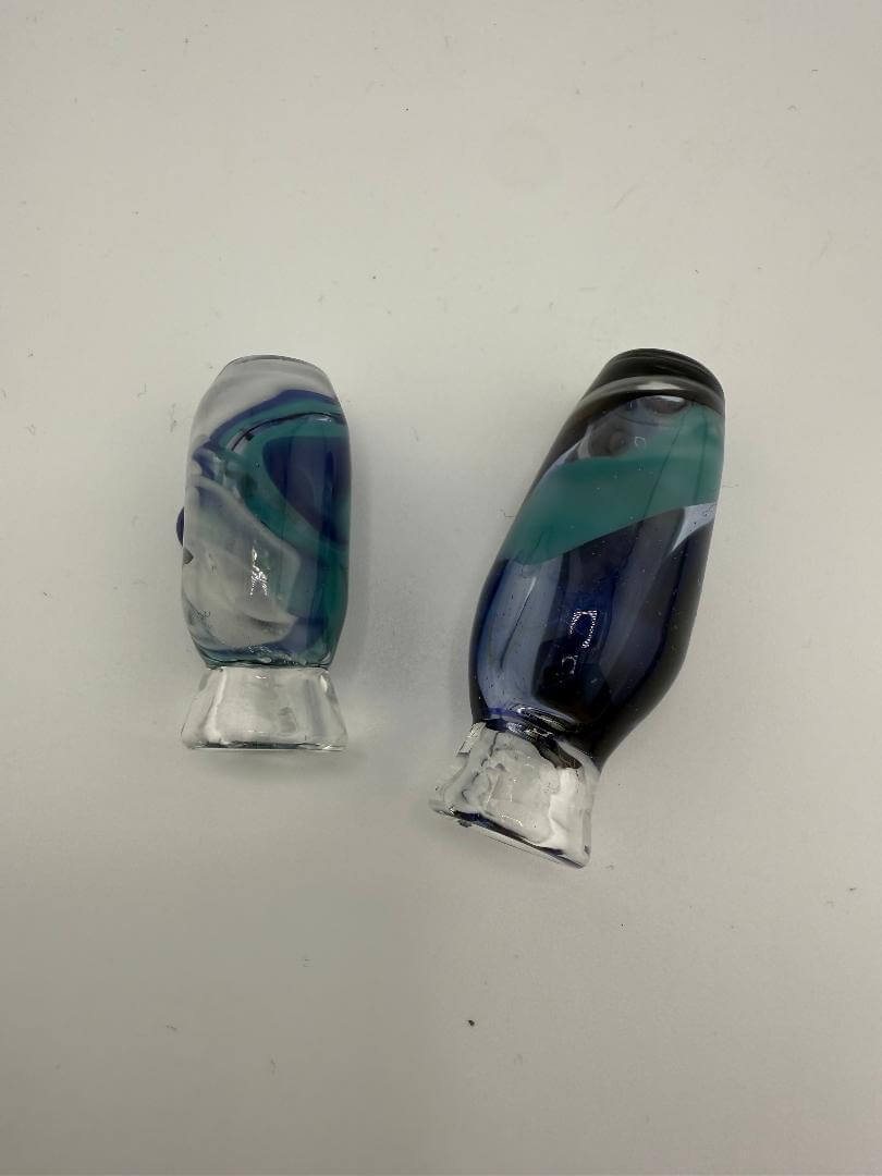 Two handcrafted glass pivot tops in blue and green swirls for Puffco Peak Pro, showcasing unique aesthetics.