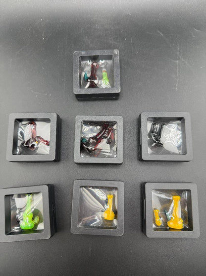 Paulson Pieces Miniature Surprise Beaker / Flower Pipe collection in display boxes showcasing intricate glass designs.