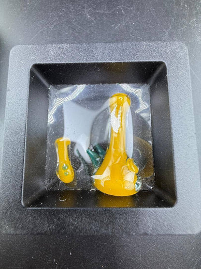 Paulson Pieces Miniature Surprise Beaker / Flower Pipe in yellow and green, displayed in a square holder.