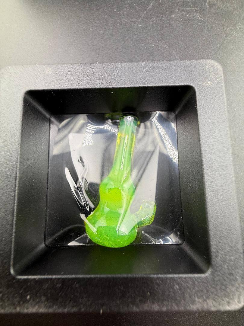 Paulson Pieces Miniature Surprise Beaker / Flower Pipe displayed in a black square dish, showcasing its vibrant green color.